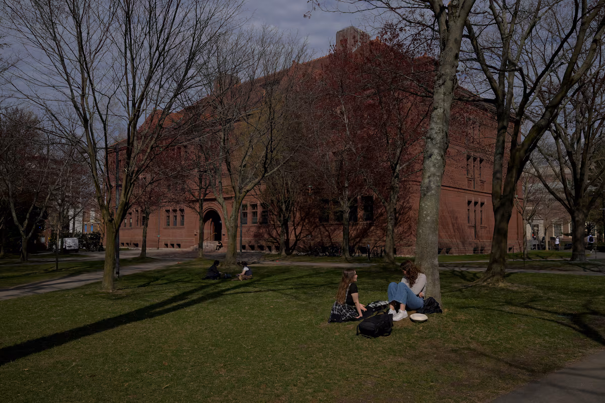 People sit on the grass at the campus of Harvard University in Cambridge, Massachusetts, U.S., April 15, 2025.